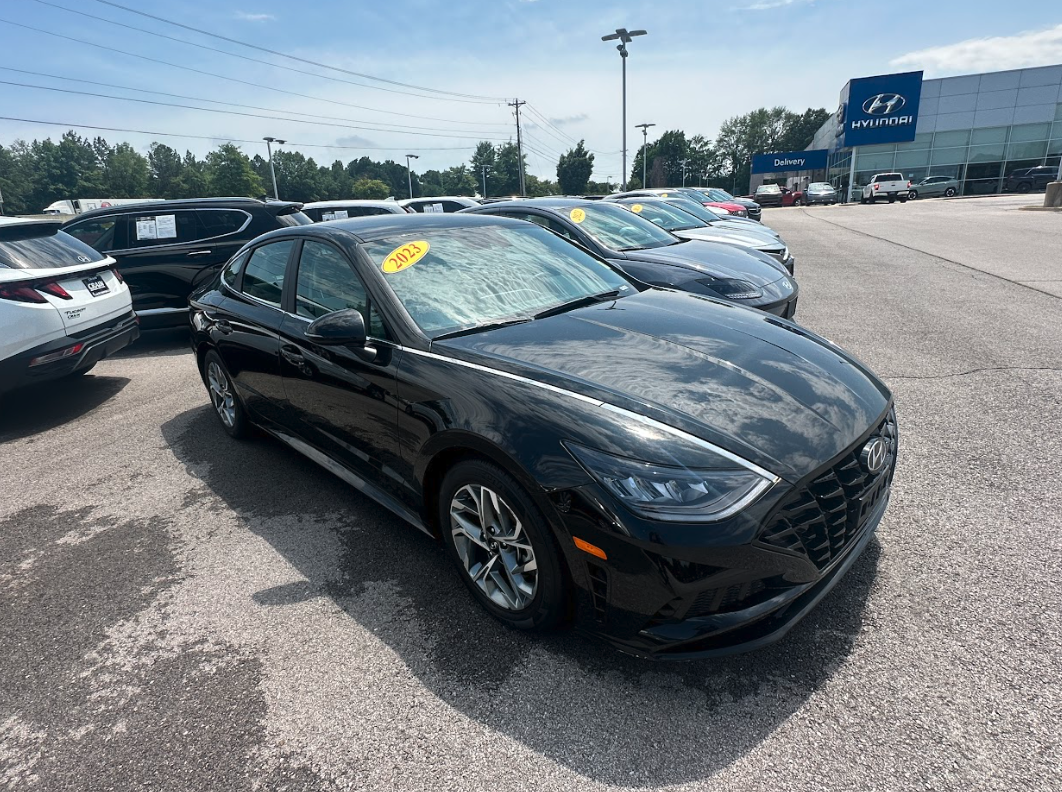 2023 black Hyundai Sonata sedan parked in the Crain Hyundai Fayetteville lot under clear skies.